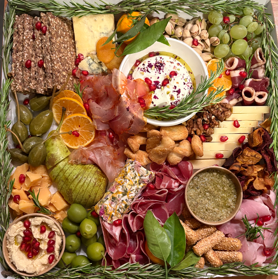 Planche de charcuterie avec fromages, viandes, fruits, noix, craquelins, trempettes et garniture au romarin.