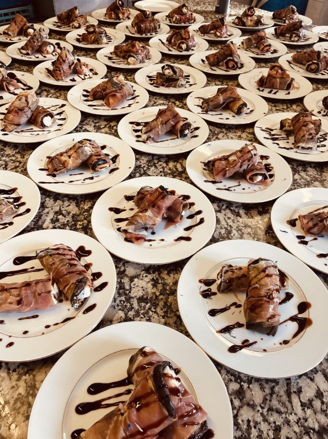 Assiettes de petits pains dessert enrobés de chocolat arrosés de sauce noire, disposés sur une surface en marbre.