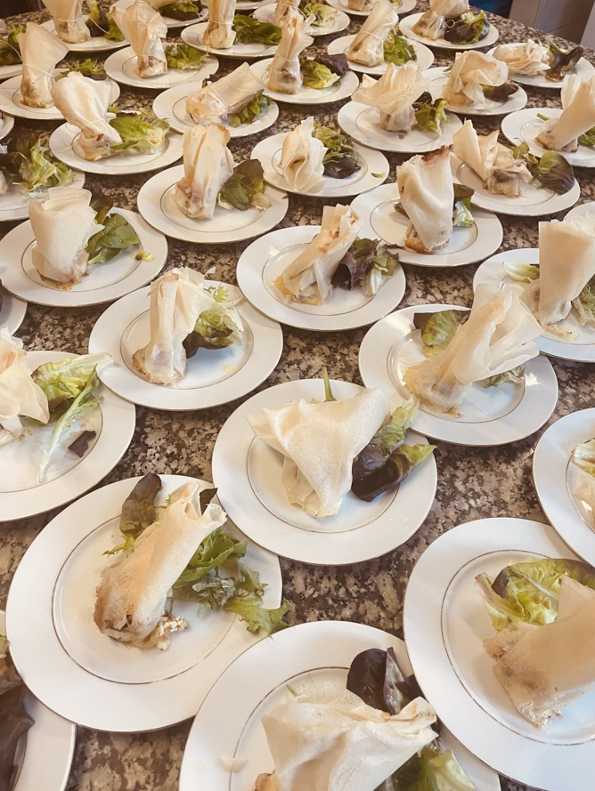 Assiettes de nourriture, chacune contenant un aliment roulé, de la laitue et de la sauce foncée, disposées sur une table.