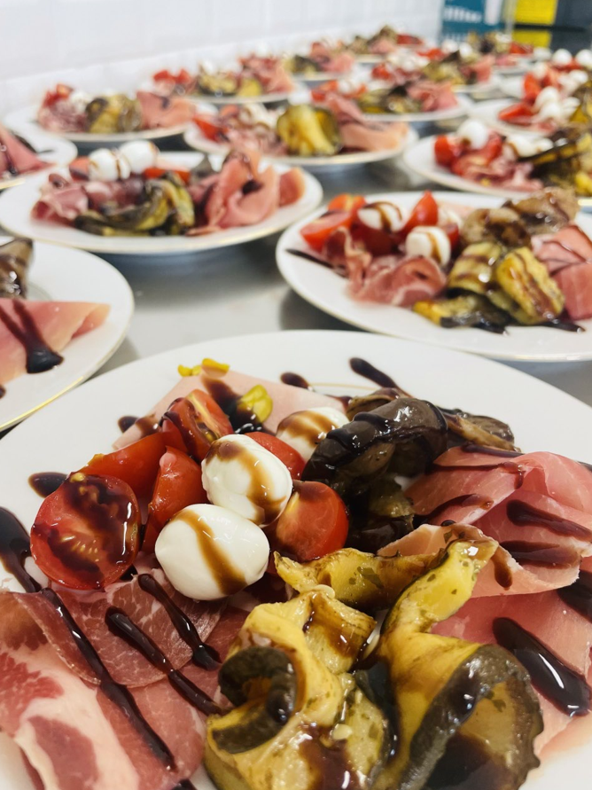 Assiettes de salades apéritives avec tomates, mozzarella, prosciutto et glaçage balsamique, prêtes à servir.