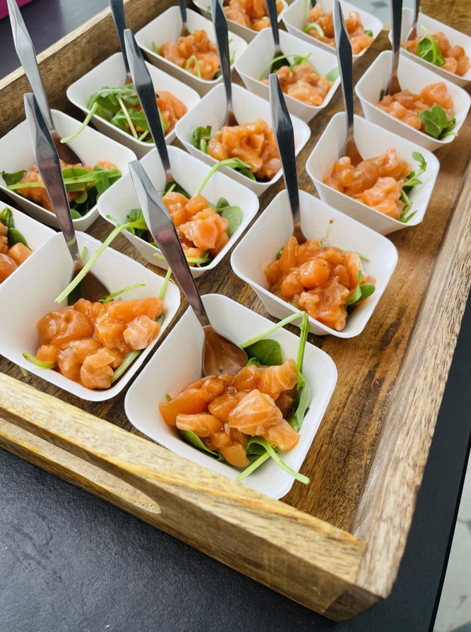 Plateau d'amuse-gueules au saumon dans des bols carrés blancs avec de petites cuillères.