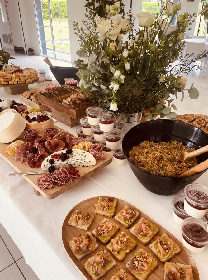 Buffet avec charcuterie, desserts et composition florale.