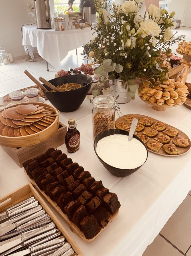 Petit déjeuner buffet avec crêpes, brownies, granola, yaourt et fleurs.