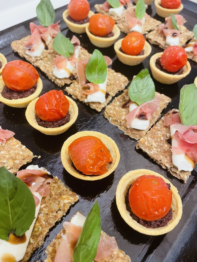 Plateau d'amuse-gueules : mini tartelettes aux tomates, craquelins au prosciutto et feuilles de basilic frais.