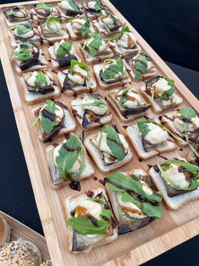 Plateau de pain grillé garni d'aubergines, de fromage, de roquette et de glaçage balsamique.