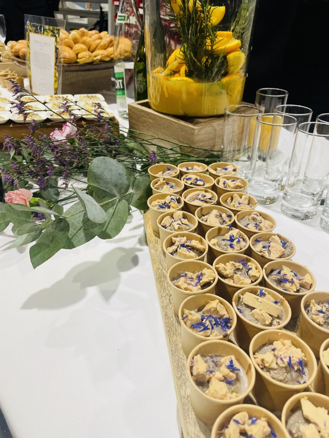 Buffet avec petits desserts, boissons et décorations florales.