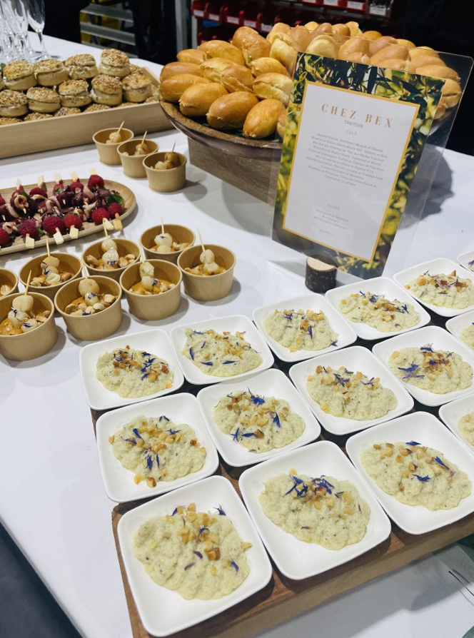 Buffet de restauration composé de plats variés : petits pains, entrées et petites assiettes carrées de risotto crémeux.