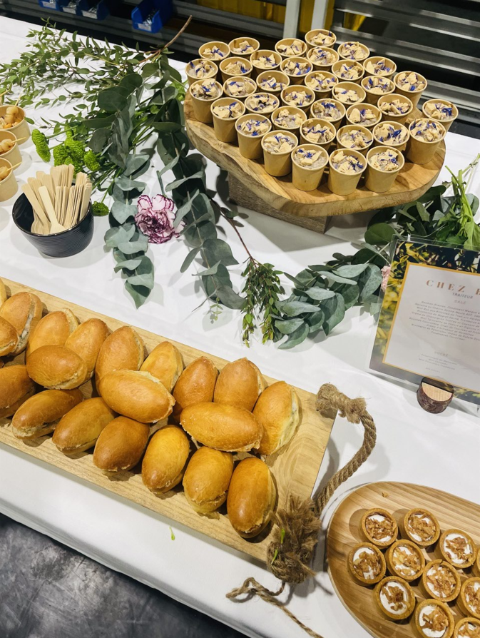 Présentation des mets : petits pains et mini desserts sur une table décorée de verdure.
