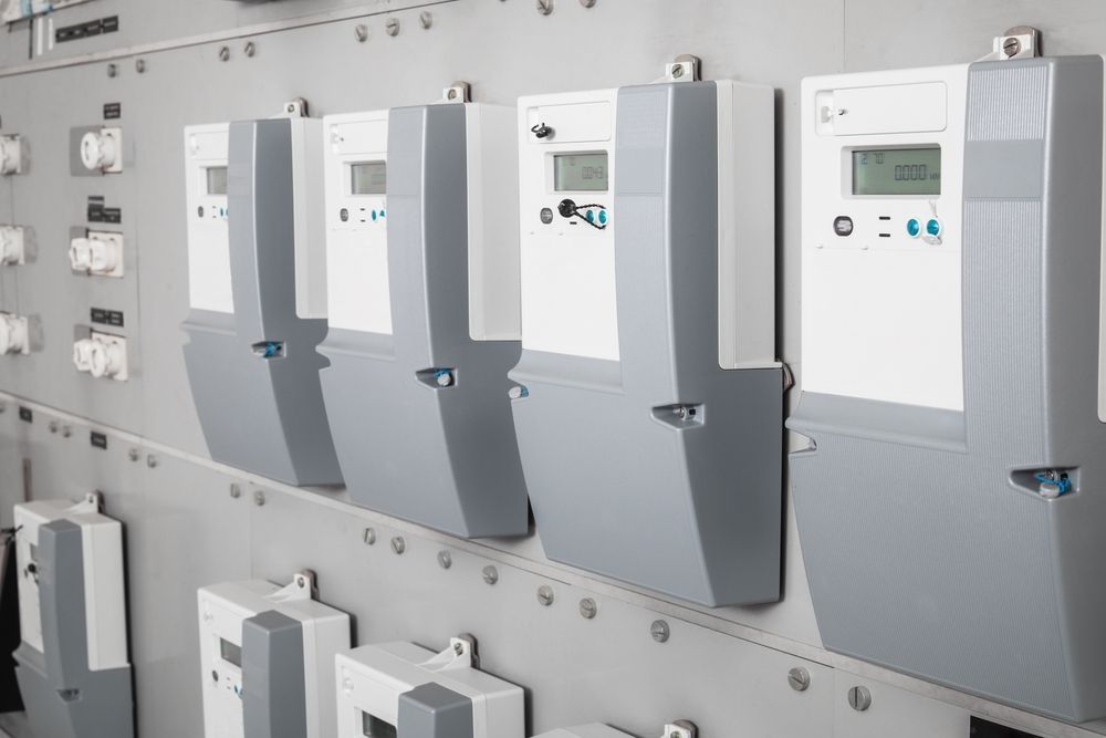 Row of white and gray electric utility meters mounted on a wall