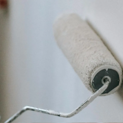 A paint roller is being used to paint a wall.