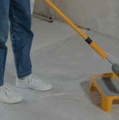 A person is painting a floor with a roller.