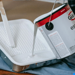 A can of glide paint is being poured into a tray