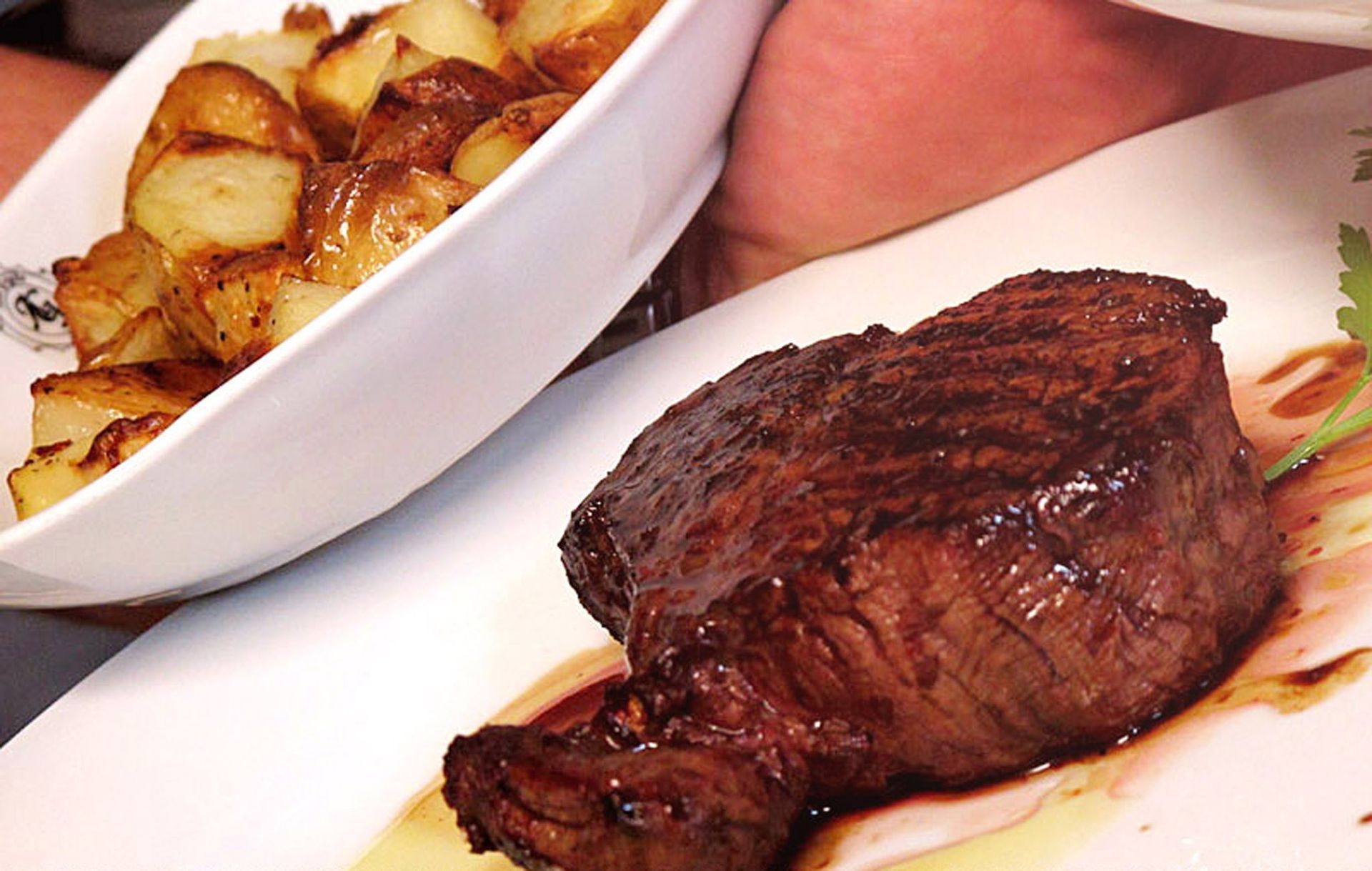 Tagliere di salumi e formaggi; le mani prendono una fetta.