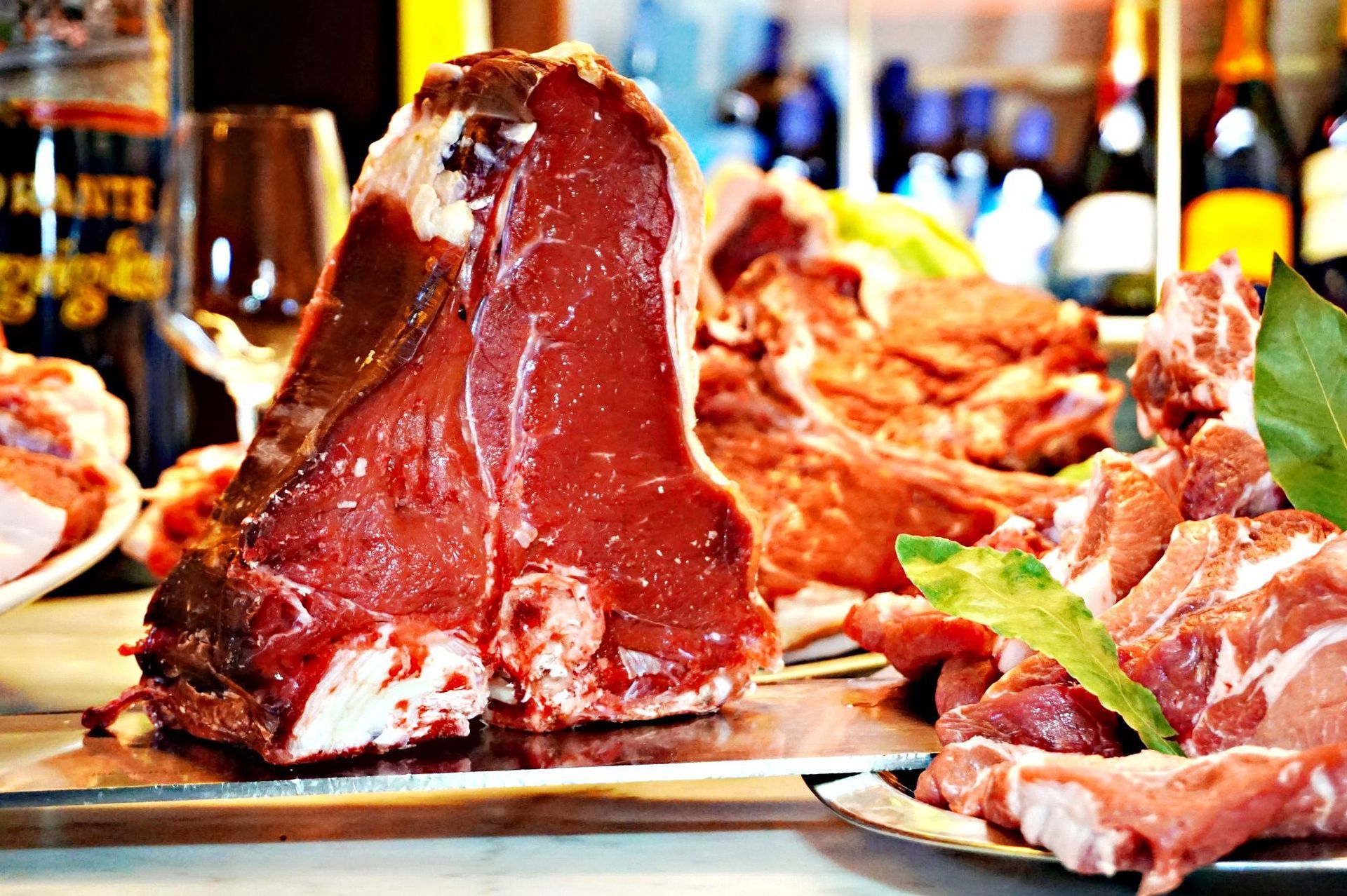 Macellaio che taglia la carne cruda con un grosso coltello su un tagliere bianco.