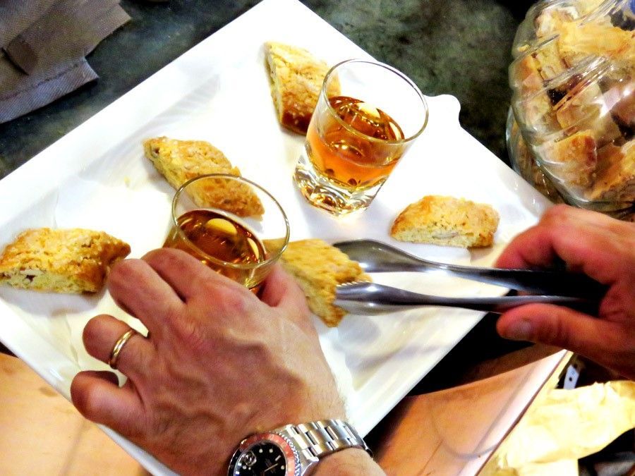 Le mani prendono biscotti e bicchieri di liquido ambrato su un piatto bianco.