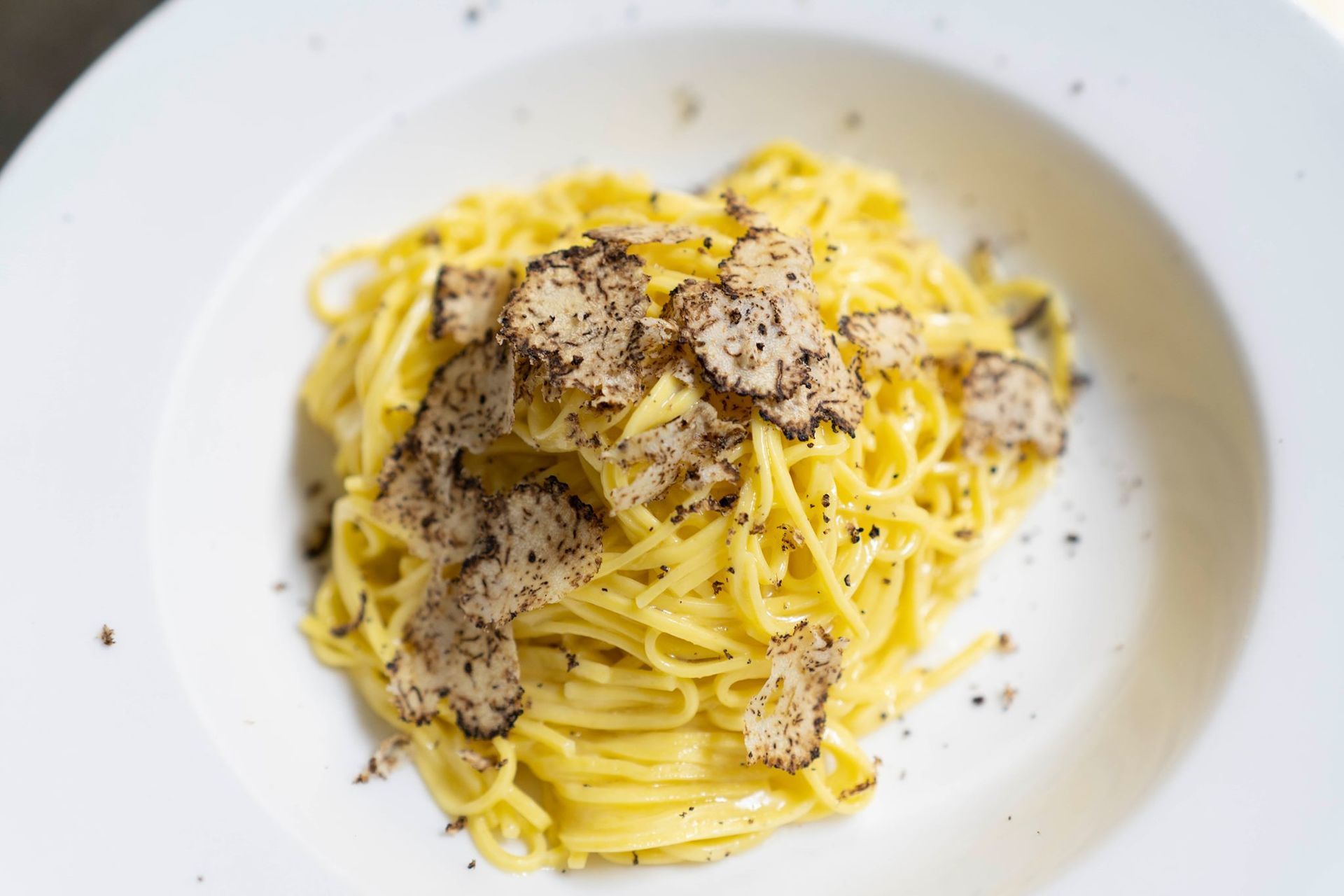 Pasta gialla con gamberi, asparagi e salsa su un piatto bianco.