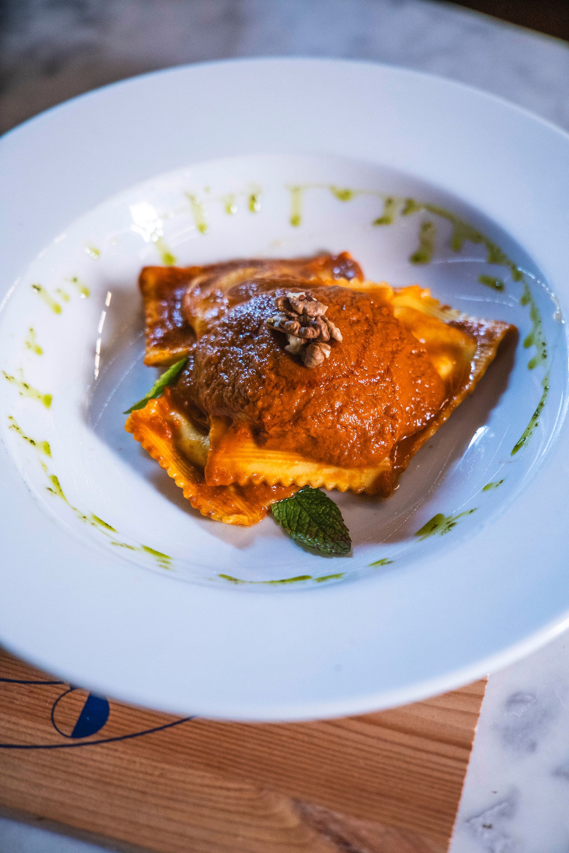 Macellaio che taglia la carne cruda con un grosso coltello su un tagliere bianco.