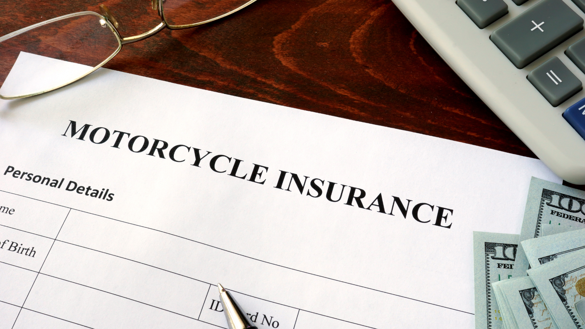 A motorcycle insurance form is on a table next to a calculator