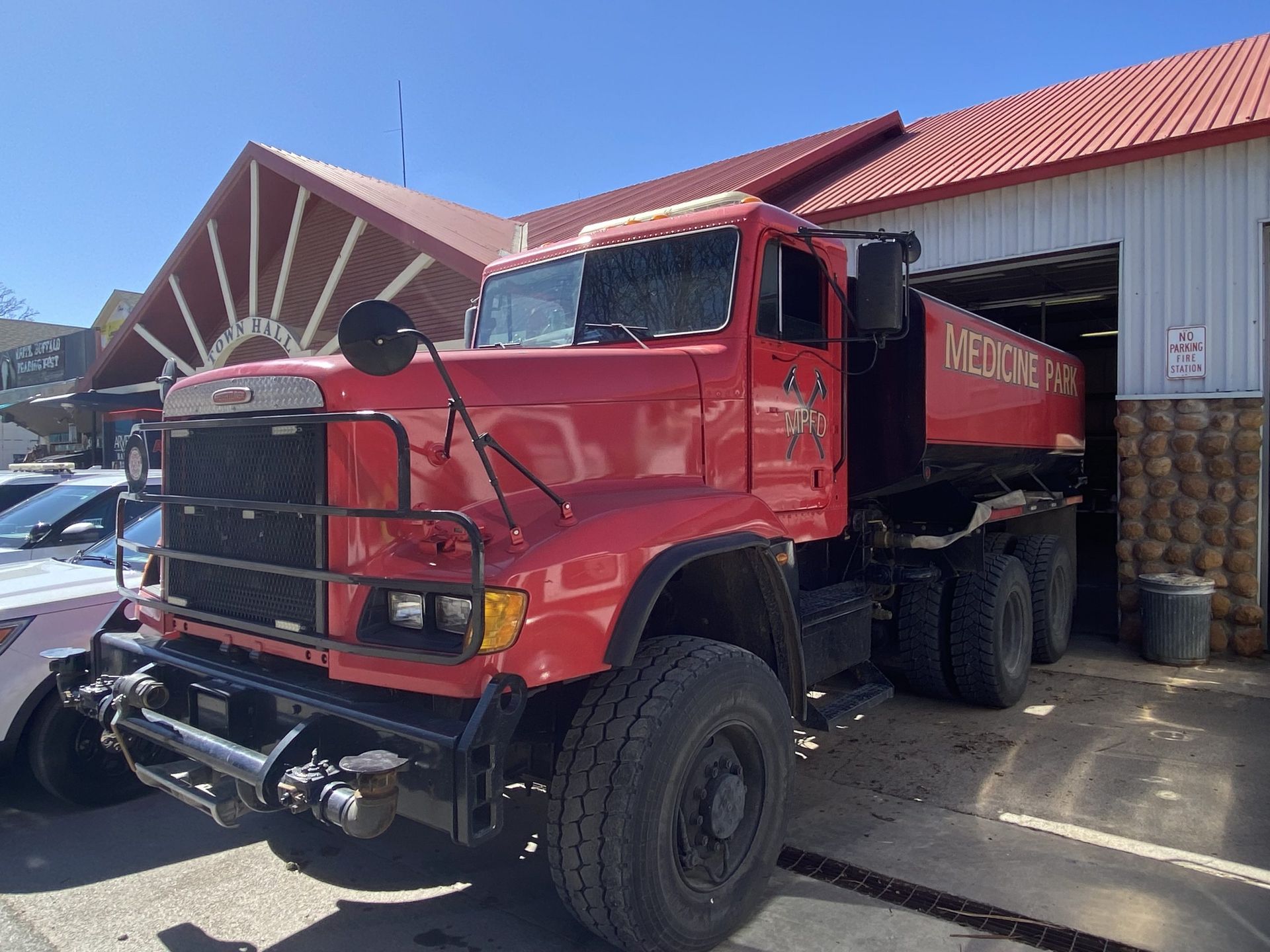 Red heavy-duty dump truck parked outside a garage with a red roof
