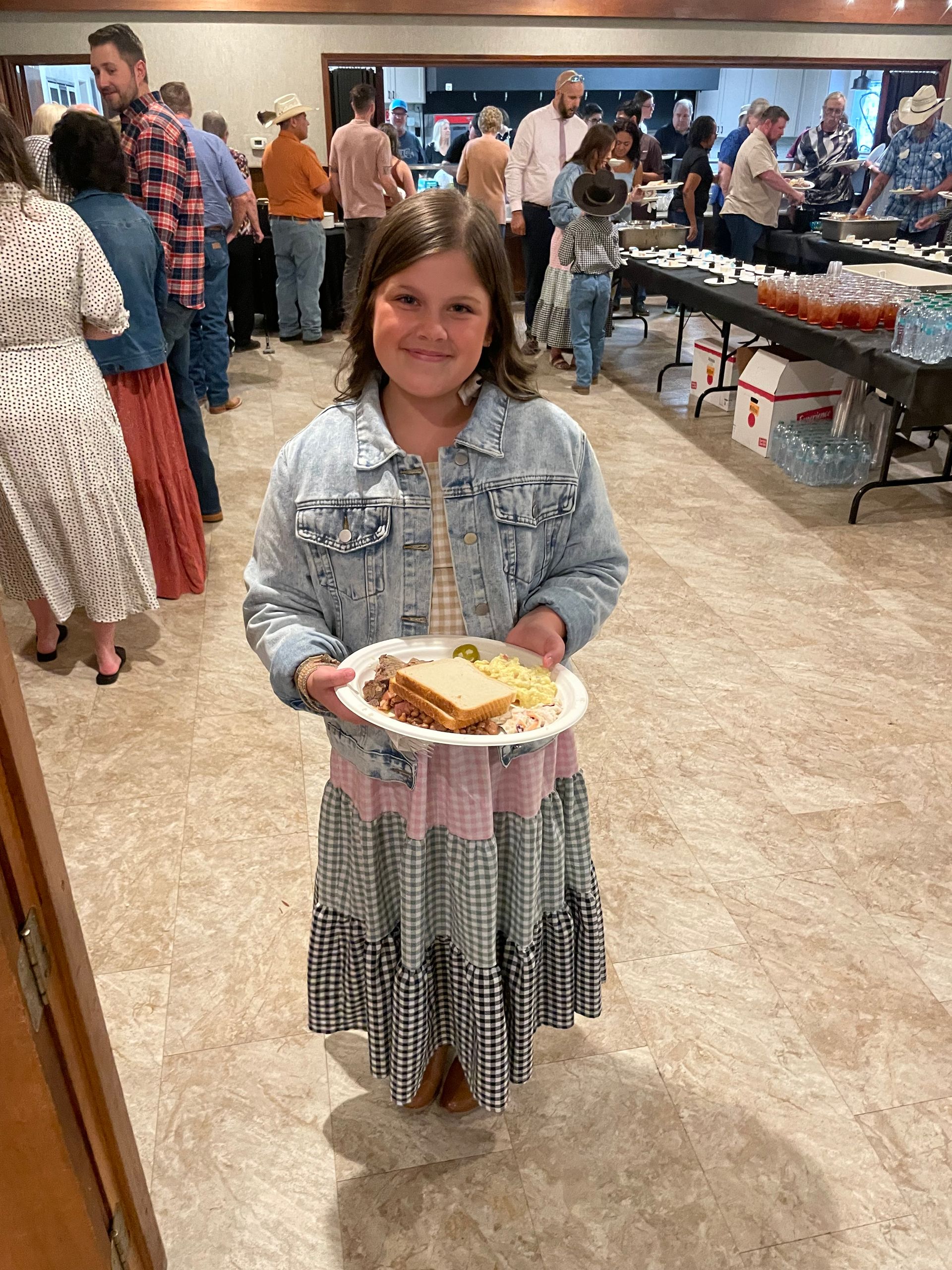 Group of people, some children, smiling at the camera near a fence and horses. One woman is in a wheelchair.