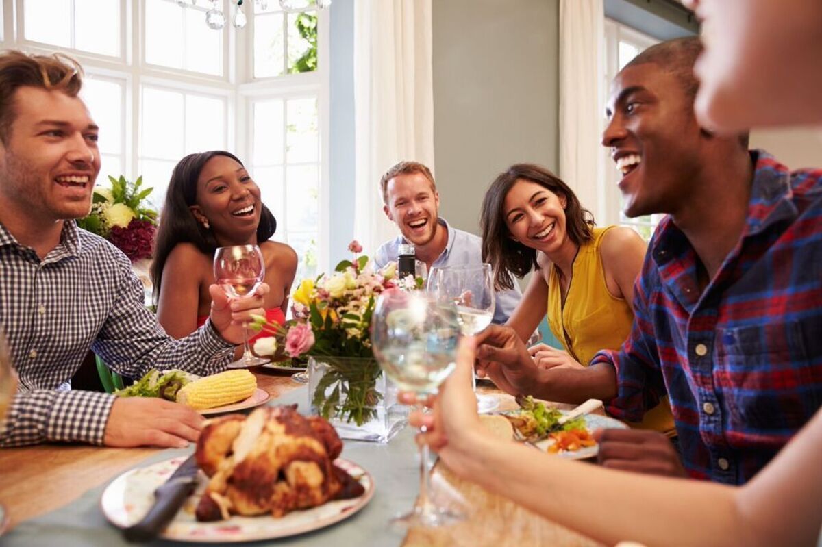 A group of people are sitting at a table eating food and drinking wine.