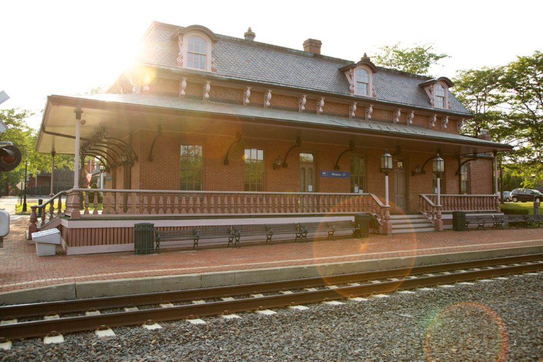 A train station with a brick building and train tracks in front of it.