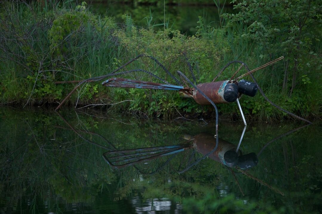 A statue of a dragonfly is standing in the water.