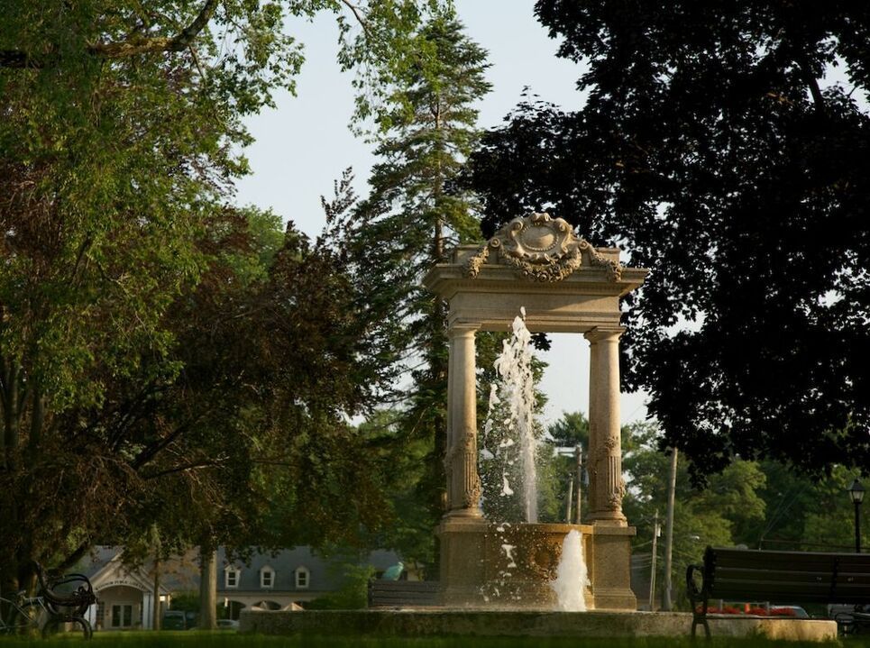 A fountain in a park with a bench in the foreground