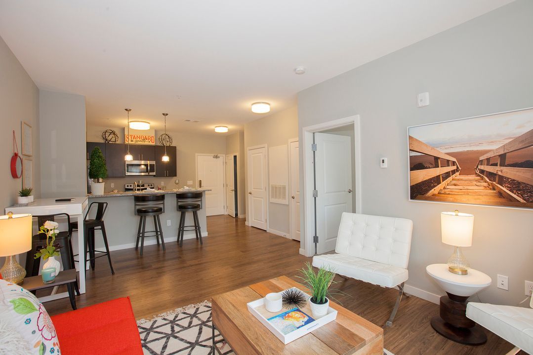 A living room with a couch , chairs , coffee table and a picture on the wall.