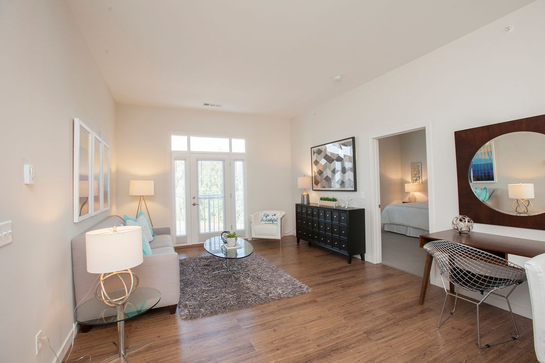 A living room with hardwood floors , a couch , a table and a mirror.