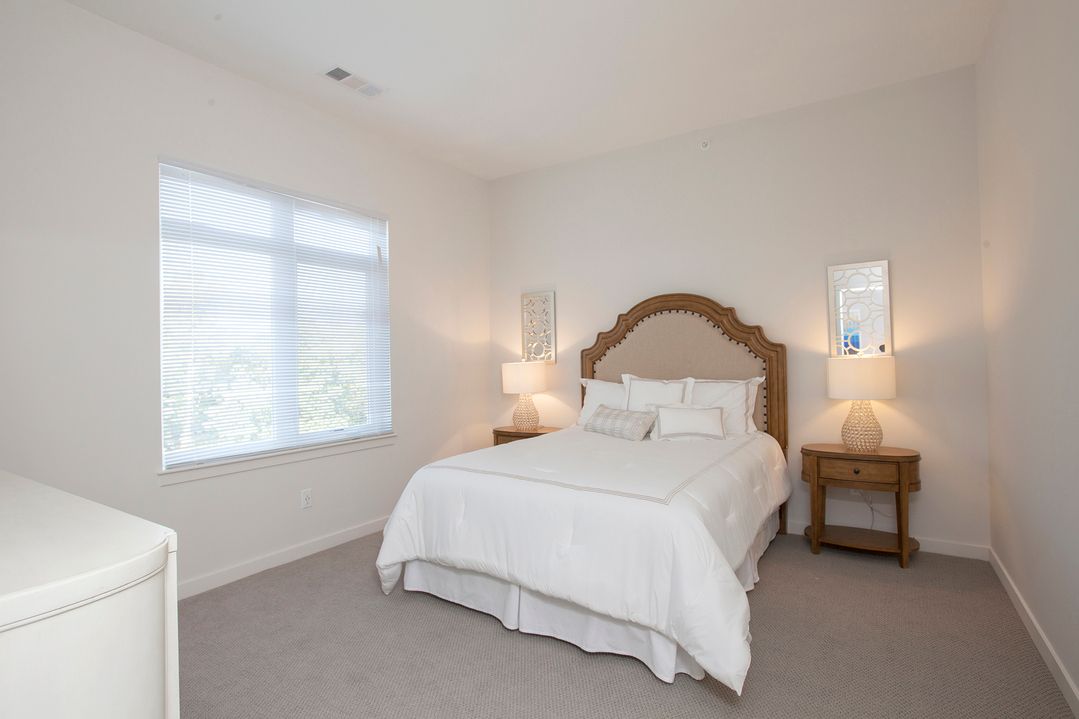 A bedroom with a bed , two nightstands , and two windows.