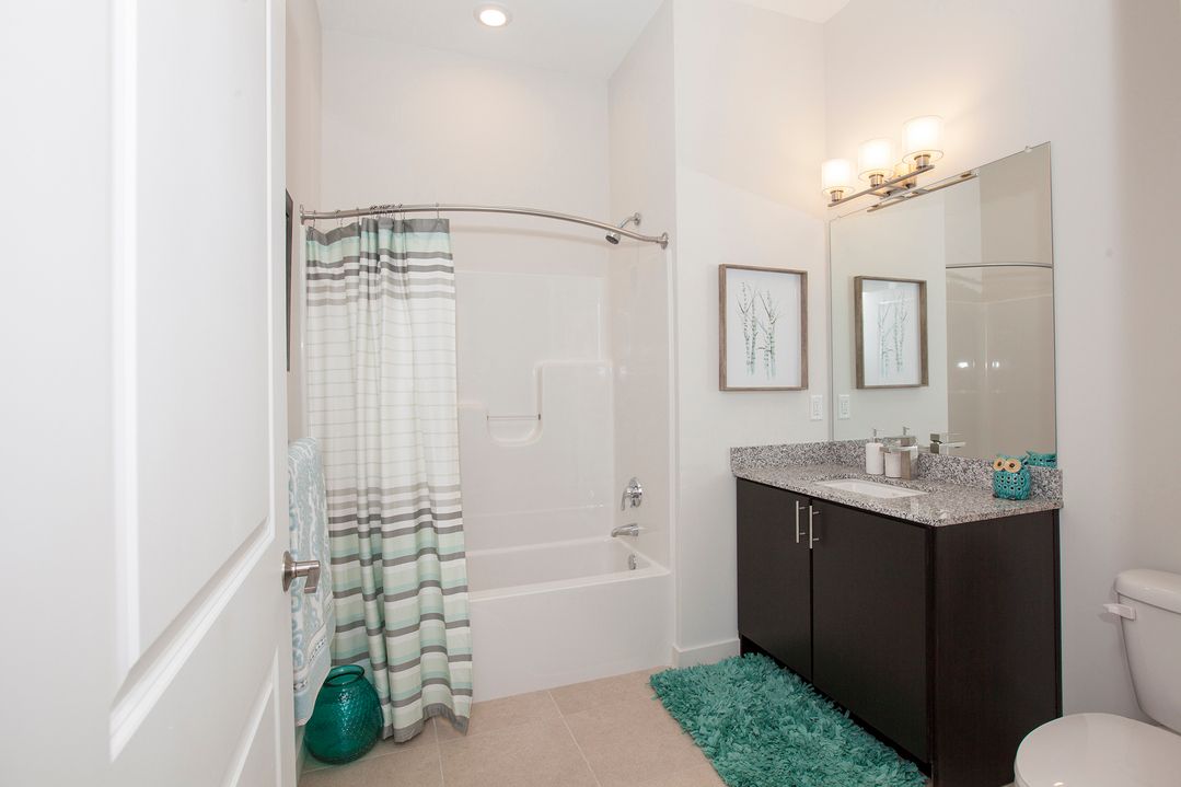 A bathroom with a tub , sink , toilet and mirror.