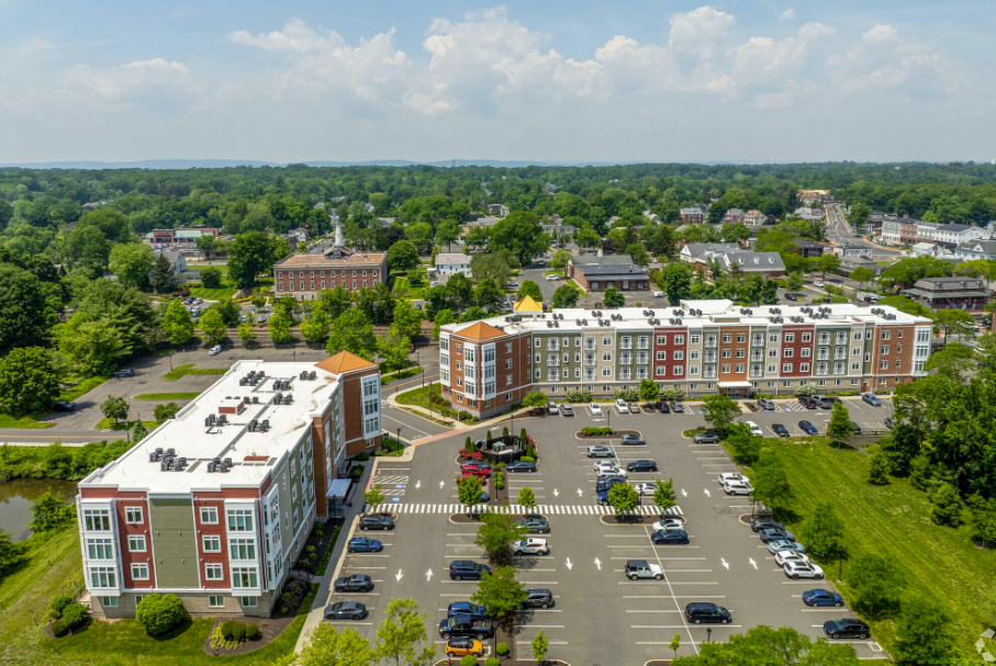 An aerial view of a large apartment building with a parking lot in front of it.