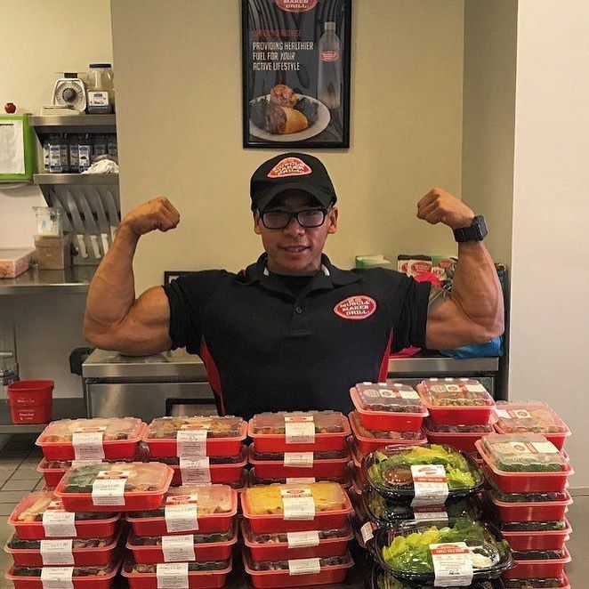 jacked man flexing his muscles next to an array of Muscle Maker grill foods