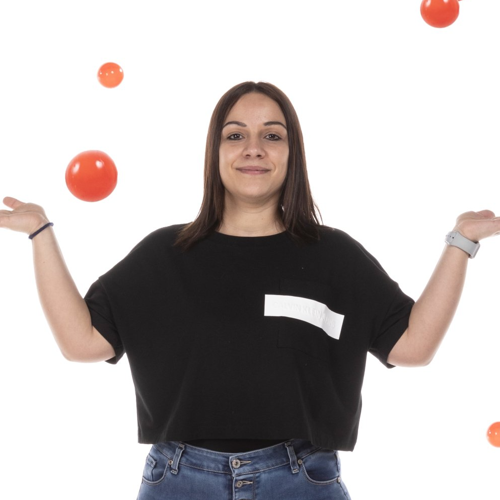 una donna che indossa una maglietta nera sta giocando con tre pomodori