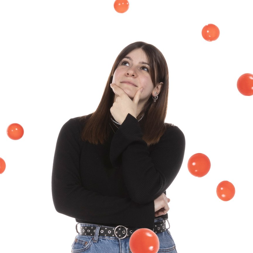 una giovane donna indossa un maglione nero e jeans e guarda in cima a un gruppo di palloncini rossi