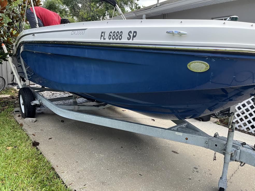 Boat on a trailer, blue hull, white trim, Florida license plate.