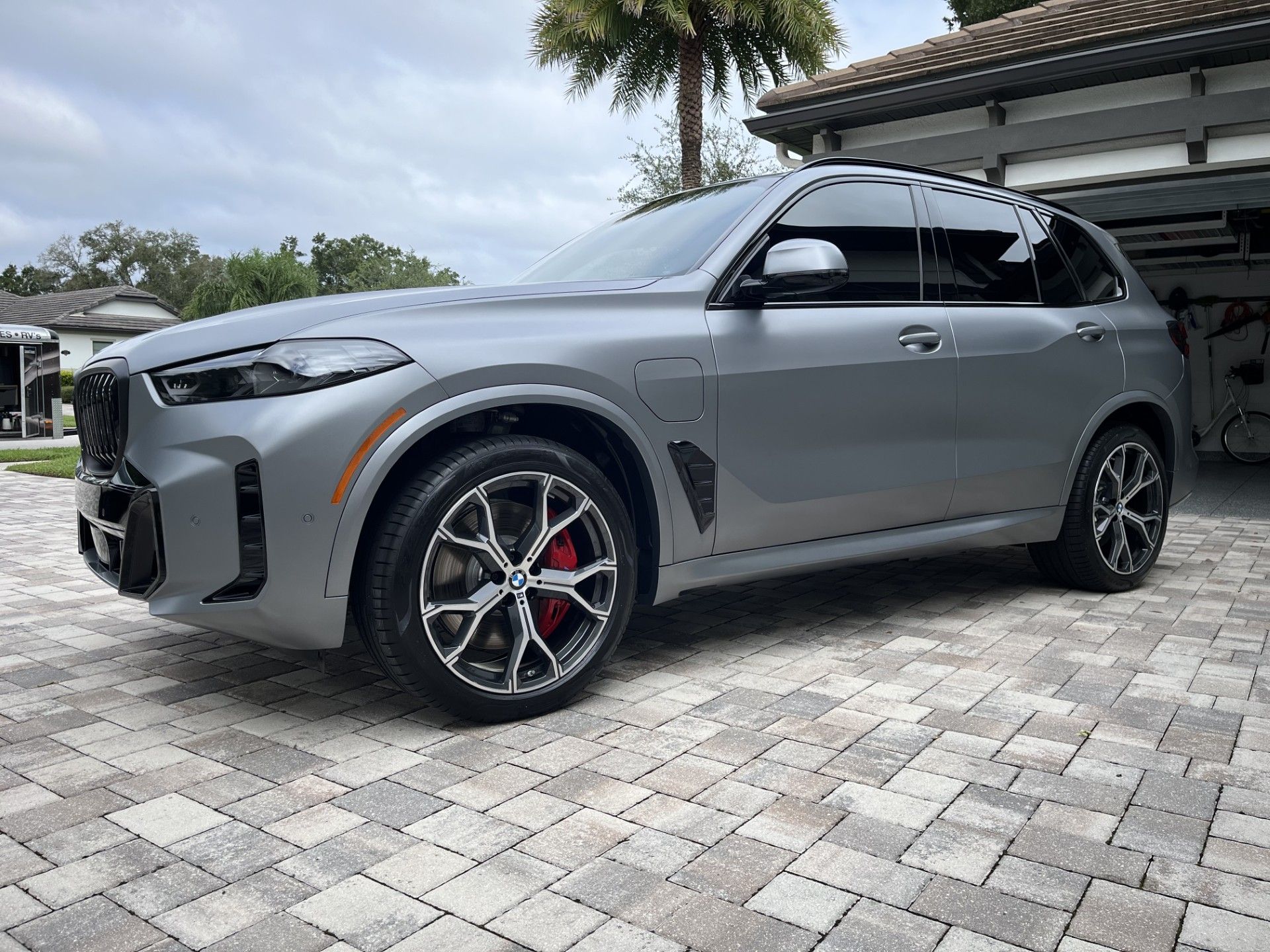 Gray and black recreational vehicle parked outdoors under a cloudy sky.