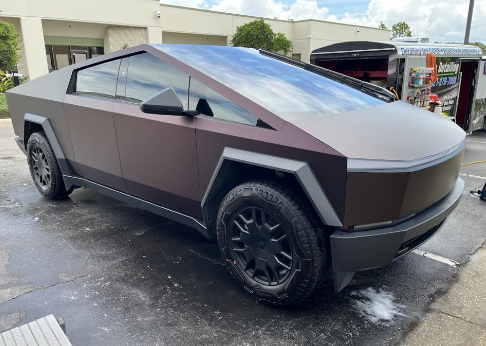 Tesla Cybertruck with dark matte finish parked outside a building.