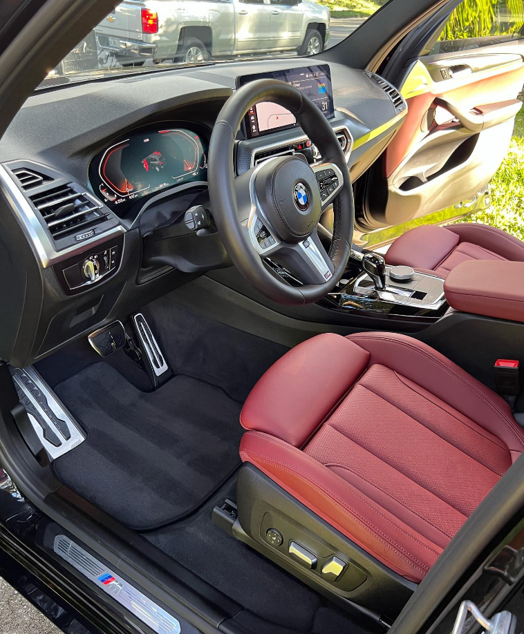 Interior of a BMW SUV with red leather seats, black dashboard, and silver accents.