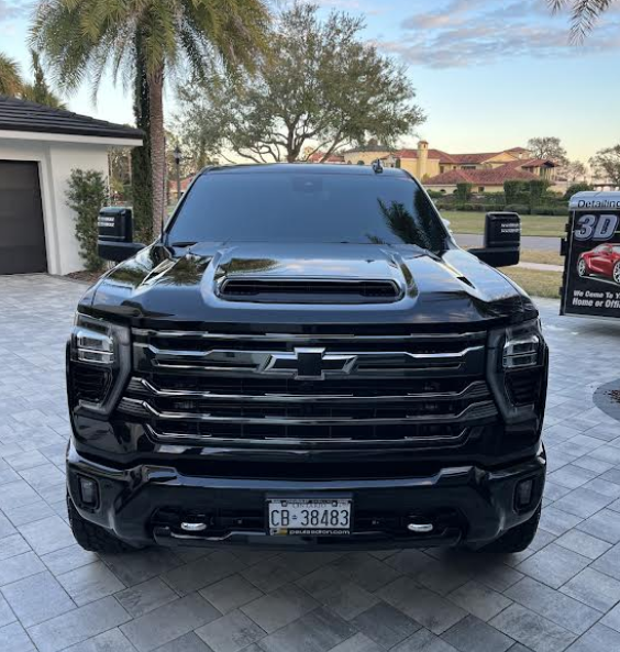 Black Chevrolet truck parked on a paved driveway in front of a house.