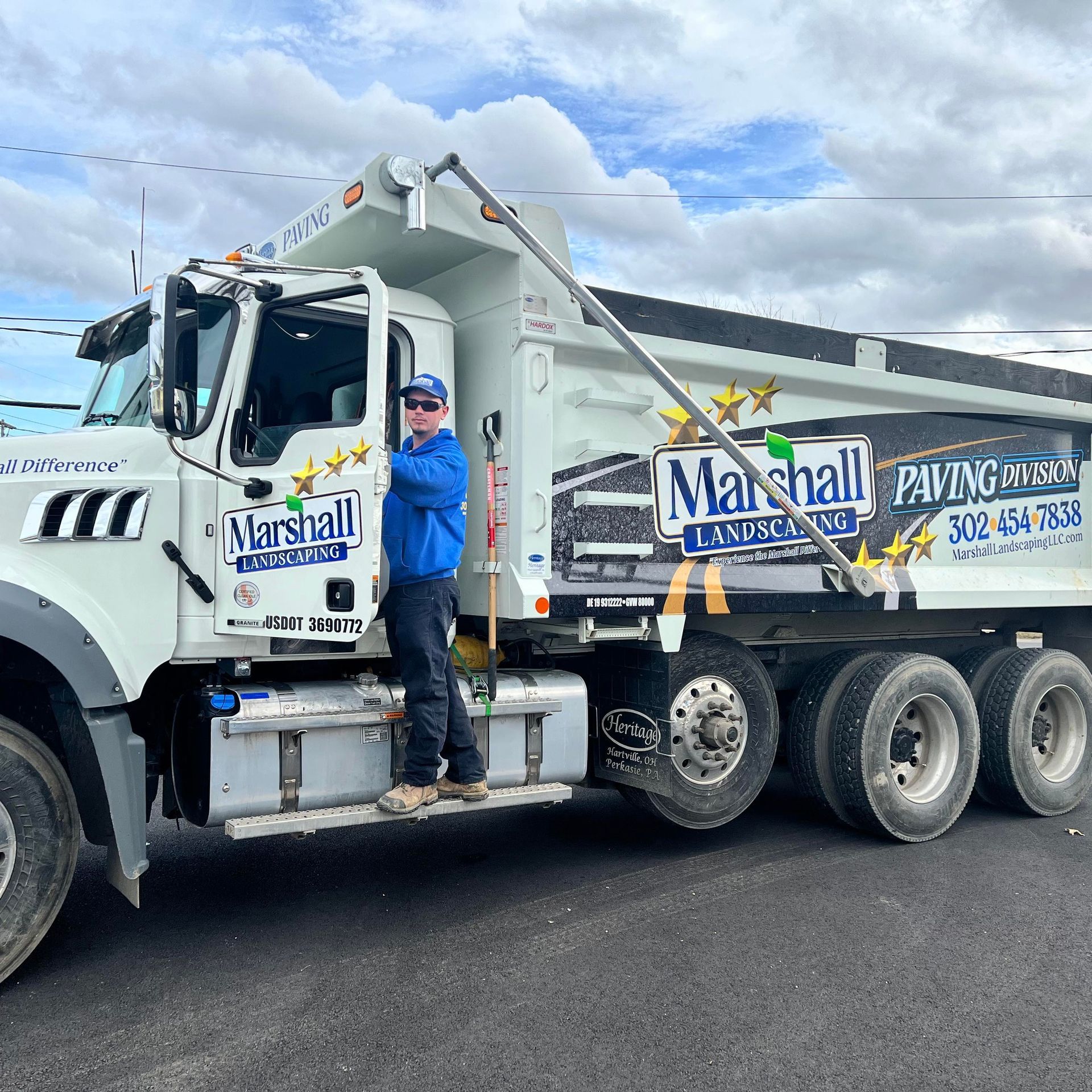 Professional lawn care team member from Marshall Landscaping standing proudly beside a well-maintained company truck in Wilmington, symbolizing reliable and prompt landscaping services.