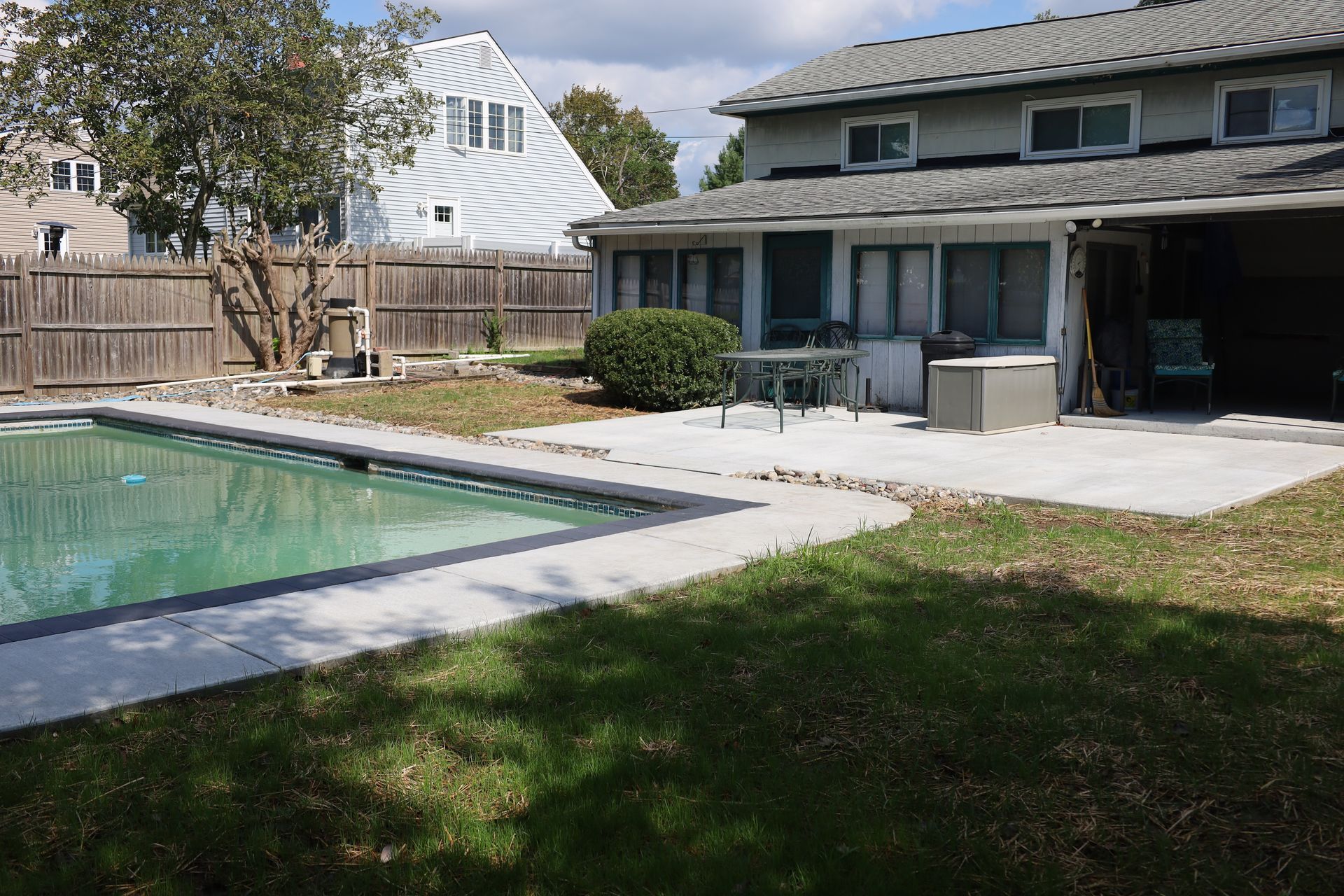 New concrete pool deck and patio in Delaware backyard with fence