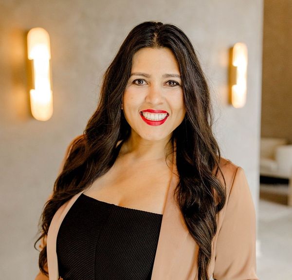 A man is holding a dog in his arms and the dog is wearing a sweater.