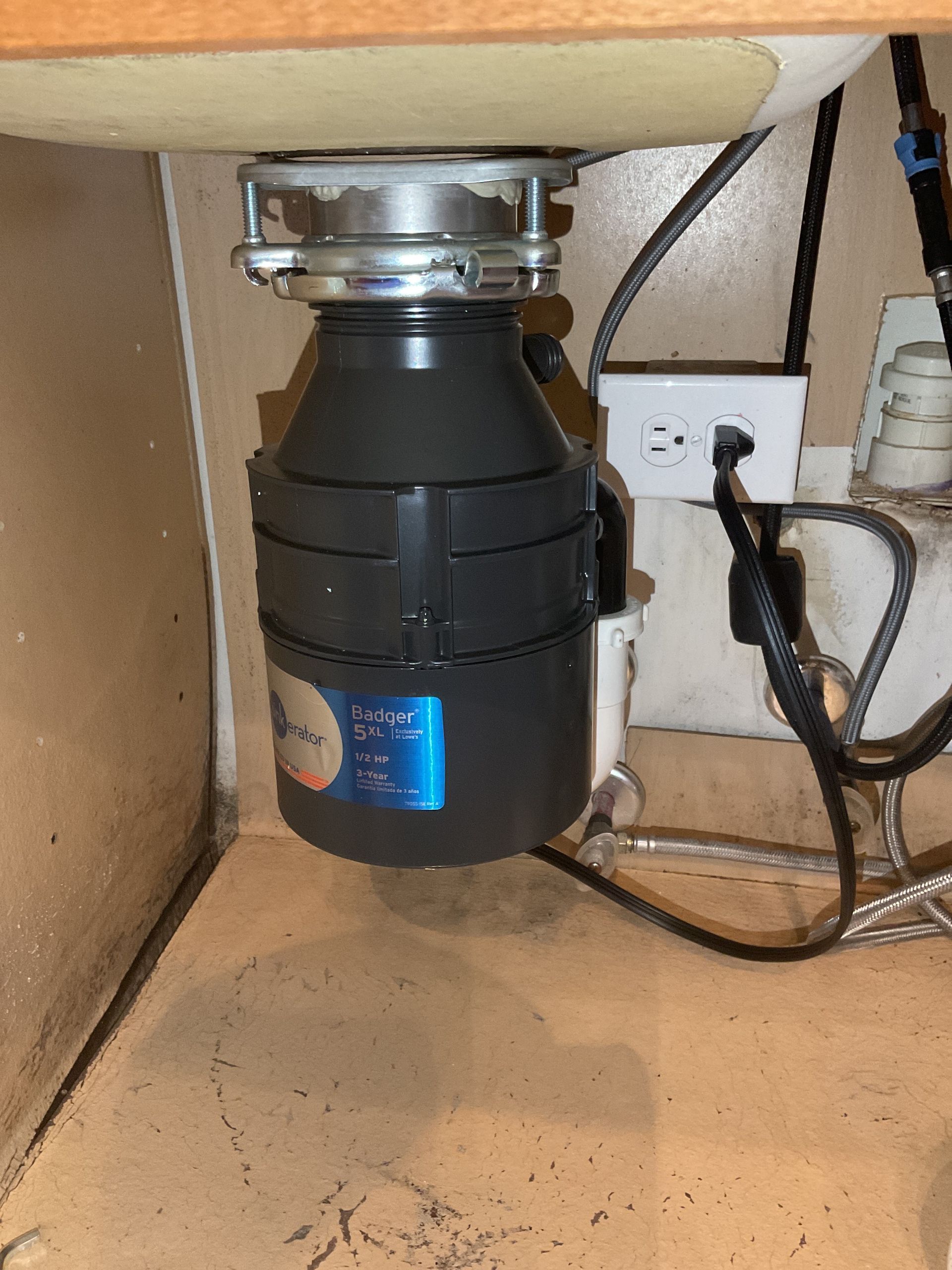 A garbage disposal is under a sink in a kitchen.