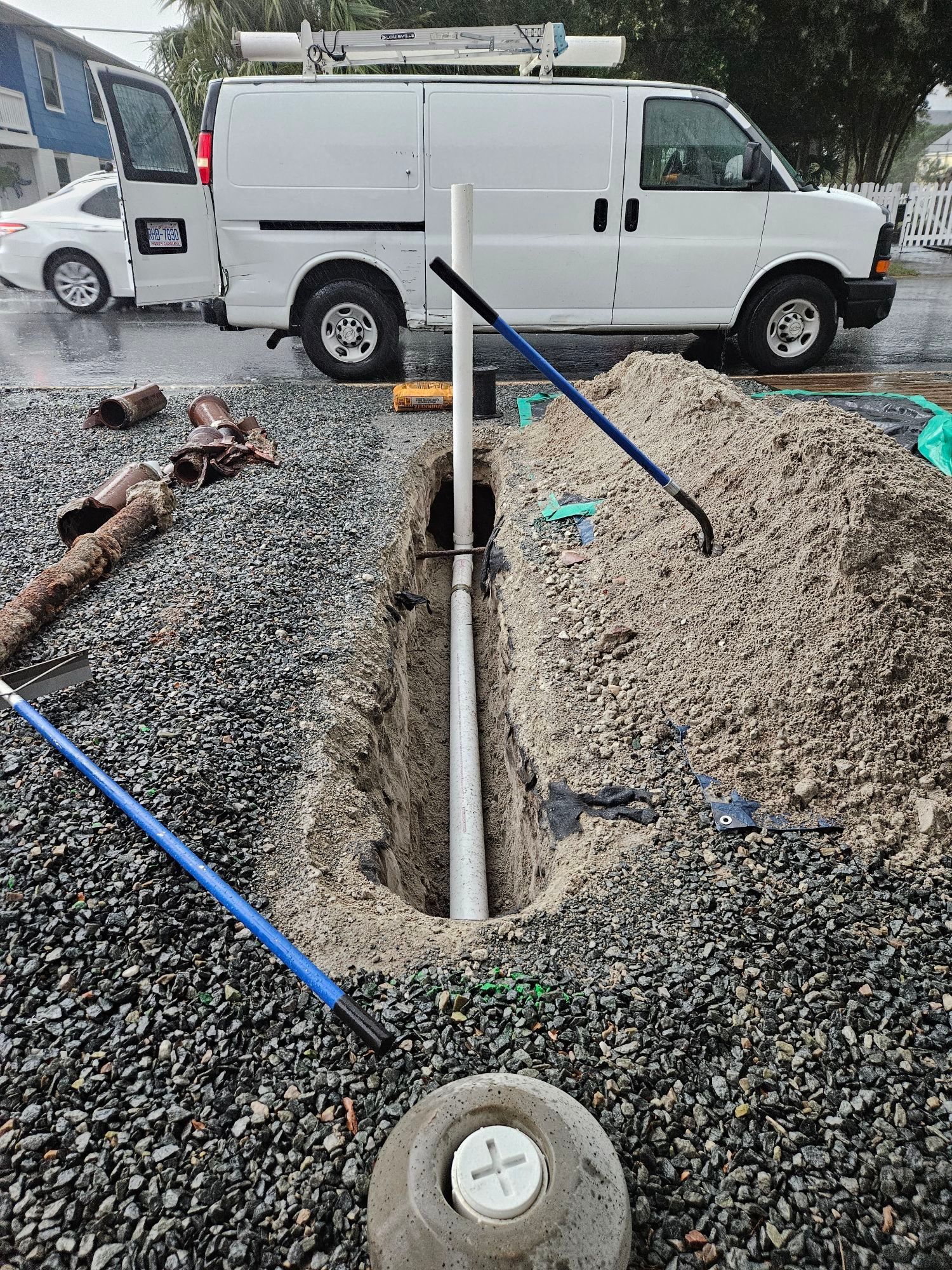A white van is parked next to a hole in the ground.