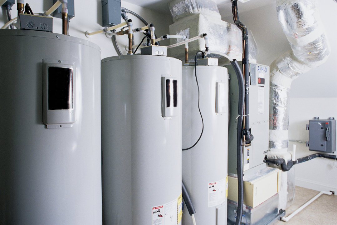 Three water heaters are sitting next to each other in a room.