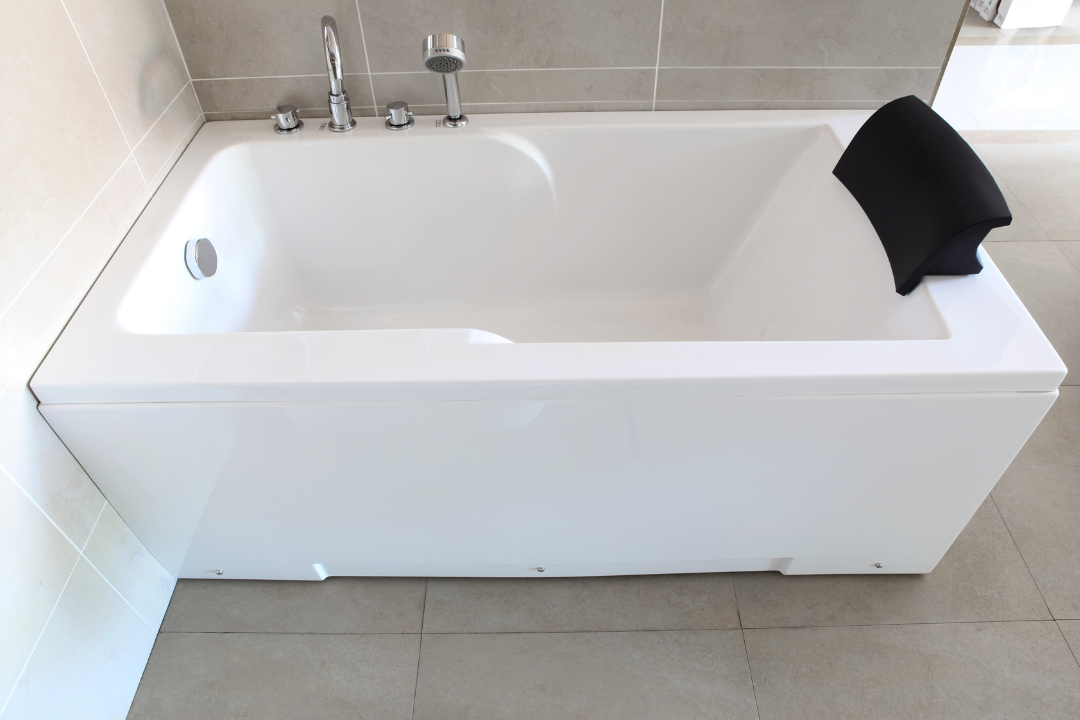 A white bathtub with a black pillow on the side