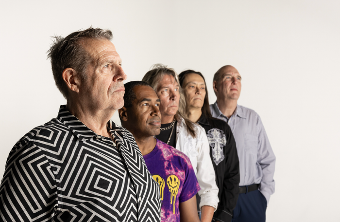 Two men standing next to each other with one holding a pink guitar