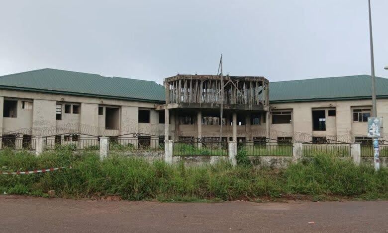 Dilapidated building with broken windows and overgrown grass.
